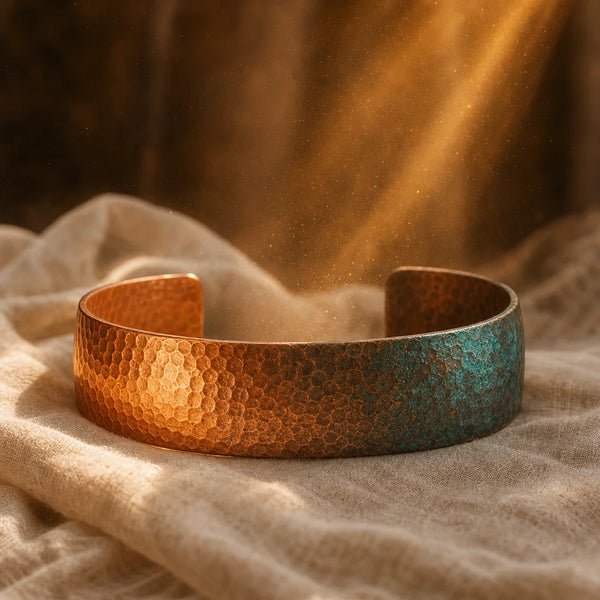 Hammered copper cuff with a green patina on linen